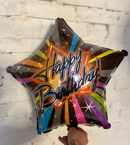 Star-shaped birthday balloon with colorful design against a white brick wall. 70's disco throwback roller rink star foil mylar helium balloon pick up or delivery Pittsburgh Lawrenceville small business